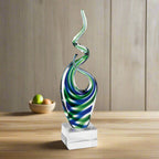 Glass sculpture with blue and green swirls on a white background